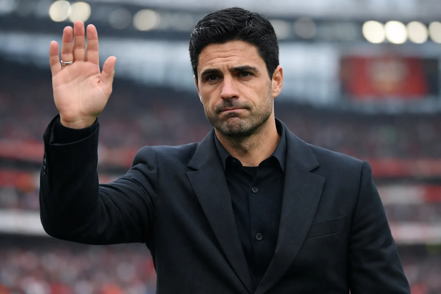 A highly detailed and recognizable representation of Mikel Arteta with a somber, apologetic expression, addressing fans after a defeat at the Emirates Stadium.