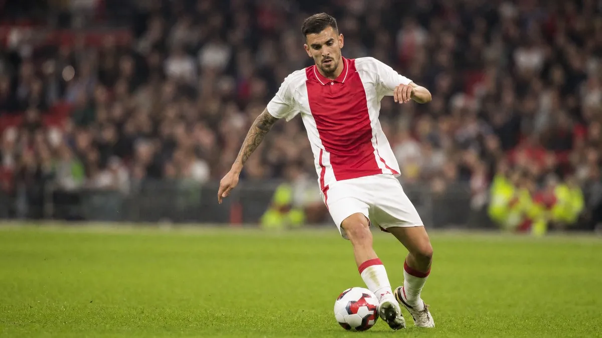 Dani Ceballos in action wearing Ajax's red and white kit, controlling the ball during an Eredivisie match in Amsterdam