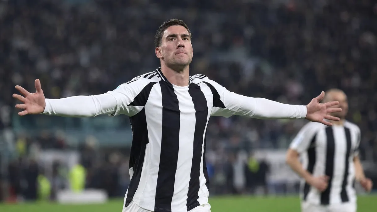 Dusan Vlahovic celebrating a goal in Juventus's black and white striped kit during a Serie A match at the Allianz Stadium in Turin