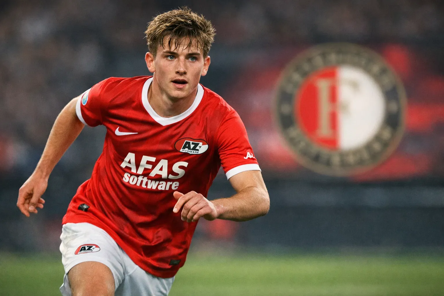 A cinematic editorial photograph of 19-year-old Kees Smit in an AZ Alkmaar home kit, featuring an accurate facial likeness with a youthful and ambitious expression, with the Feyenoord crest subtly displayed on a blurred digital screen in the background.
