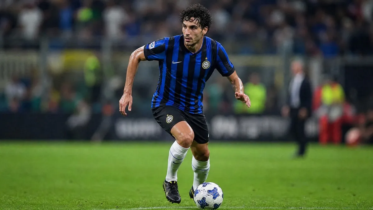 Alessandro Bastoni in action, wearing his black and blue Inter Milan kit, dribbling the ball during a Serie A match.