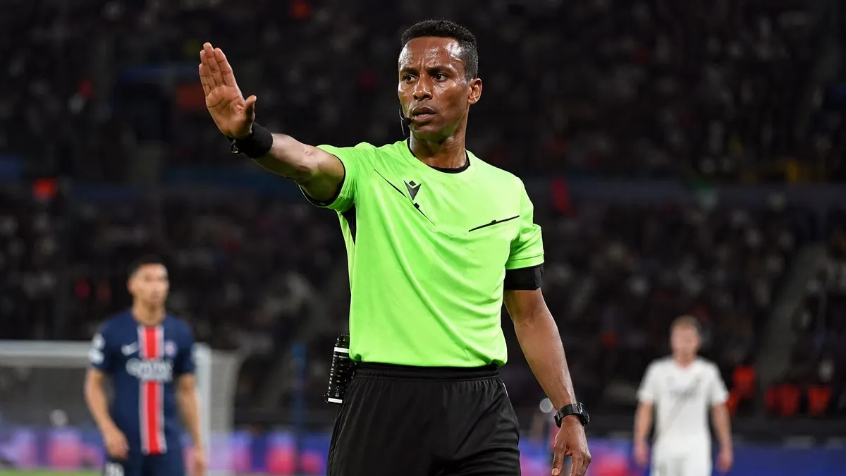 Omar Artan, Somali referee, in light green UEFA kit on pitch, signaling during a major UEFA Super Cup final.