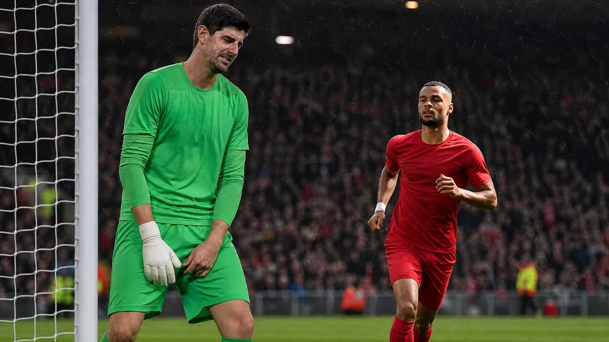 Thibaut Courtois reacts to an injury as Cody Gakpo runs in red amid football transfer rumors.